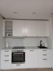 a white kitchen with white cabinets and a sink at City center apartment in Klaipėda