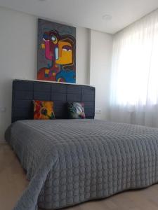 a large bed in a bedroom with a painting on the wall at City center apartment in Klaipėda