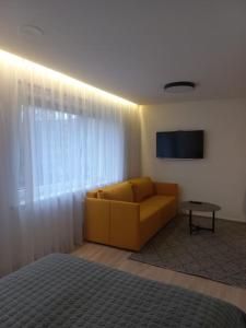 a living room with a yellow couch and a television at City center apartment in Klaipėda