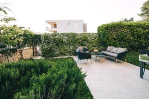 een patio met stoelen en een tafel in de tuin bij Edonia Garden Home Comfortable & stylish duplex apartment with relaxing private garden in Brodarica