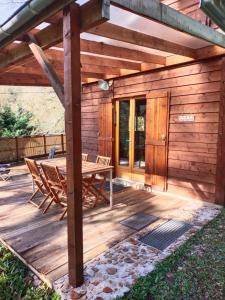 a wooden deck with a table and chairs on it at Chalet 1 chambre in Chenecey-Buillon