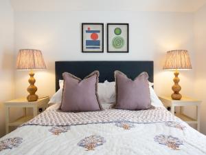 a bedroom with a bed with purple pillows and two lamps at The Fold in Charlbury