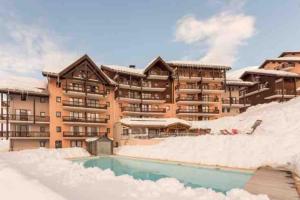 a large building with a swimming pool in the snow at Appartement pied des pistes Valmeinier in Valmeinier