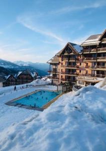 a ski lodge with a swimming pool in the snow at Appartement pied des pistes Valmeinier in Valmeinier