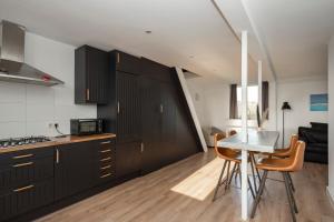 a kitchen with black cabinets and a table with chairs at Sky View in Tilburg