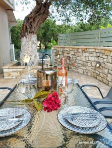 een glazen tafel met borden en een fles wijn bij Spiro's cottage by Alegria apartments in Vlachopoulátika
