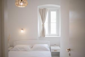 a white bedroom with a bed and a window at Sea Gate Apartment in Zadar