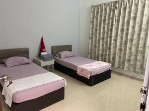 een slaapkamer met 2 bedden en een raam met gordijnen bij Homestay Taman Sri Nibong 庆丰园 in Nibung Tebal