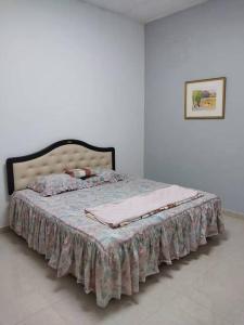 een slaapkamer met een bed met een deken erop bij Homestay Taman Sri Nibong 庆丰园 in Nibung Tebal