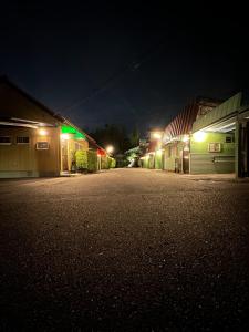 una calle vacía por la noche con luces verdes en ホテル水明, en Koriyama