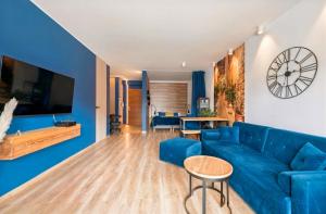 a living room with a blue couch and a table at Riverview Apartament Waterline SPA & Pool in Gdańsk