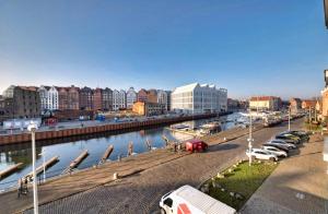 a city with cars parked next to a river at Riverview Apartament Waterline SPA & Pool in Gdańsk