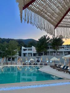 a swimming pool with chairs and umbrellas next to a building at Mythical Coast Wellness Retreat in Mytilini