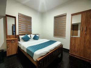 sypialnia z dużym łóżkiem z niebieskimi poduszkami w obiekcie Multiple Stories, Wayanad w mieście Wayanad