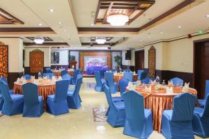 Clifton International Hotel في الفجيرة: قاعة احتفالات مع طاولات مستديرة وكراسي زرقاء