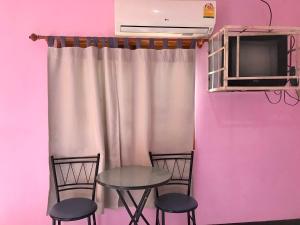 einen Tisch und zwei Stühle in einem Zimmer mit einer rosa Wand in der Unterkunft แสงสง่ารีสอร์ท Saeng Sa-Nga Resort 