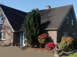 a house with a tree and flowers in front of it at Ferienwohnung im Fehnland 35667 in Uplengen