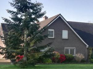 a house with a tree in front of it at Ferienwohnung im Fehnland 35667 in Uplengen