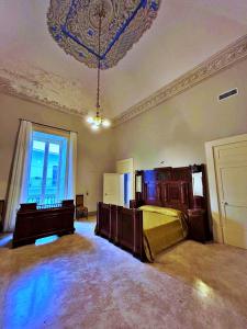 una grande camera con un letto e un lampadario a braccio di Palazzo Galluccio a Galatina