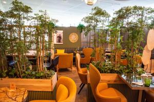 a restaurant with orange chairs and tables and plants at Pullman Paris Centre - Bercy in Paris