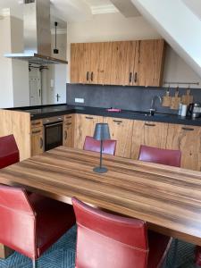 cocina con mesa de madera y sillas rojas en Luxus Lindenhof Apartments -Ferienwohnungen in Friesland an der Nordsee am Naturschutzgebiet Urwald, en Neuenburg
