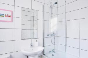La salle de bains blanche est pourvue d'une douche et d'un lavabo. dans l'établissement Cosy 3 bedroom house near Anfield Stadium, à Liverpool