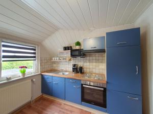 cocina con armarios azules y nevera azul en Ferienwohnung im Fehnland 35667, en Uplengen