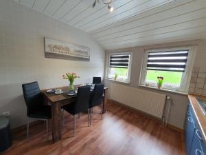 a dining room with a table and chairs and two windows at Ferienwohnung im Fehnland 35667 in Uplengen +14 photos