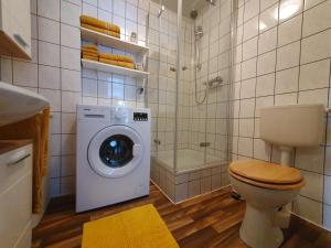 a bathroom with a washing machine and a toilet at Ferienwohnung im Fehnland 35667 in Uplengen