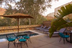 un patio con mesas y sillas junto a una piscina en Chez Ichou, en Aït Idaïr
