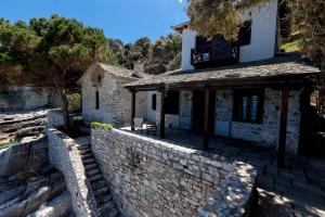 a stone house with a stone wall next to a building at Big Blue Pelion in Pilion