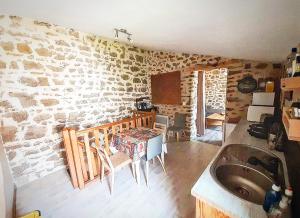 cocina con pared de piedra y fregadero en Gîte des fauvettes, en Lorlanges