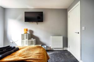 a bedroom with a bed and a flat screen tv on the wall at Hudson Apartment in East Kilbride
