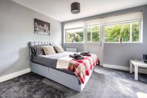Un dormitorio con una cama y dos ventanas. en Hudson Apartment, en East Kilbride