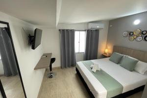 1 dormitorio con 1 cama grande y TV en Ayenda 12 Nights, en Medellín