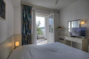 ein Schlafzimmer mit Bett, Fernseher und Fenster in der Unterkunft Gina Bed & Breakfast in Tisno