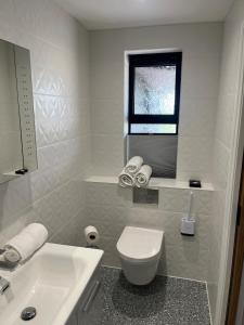 a white bathroom with a toilet and a sink at The Retreat Field View in Great Maplestead