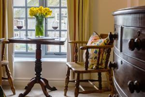 um quarto com uma mesa e uma cadeira e um vaso de flores em The Bull at Foolow em Hucklow