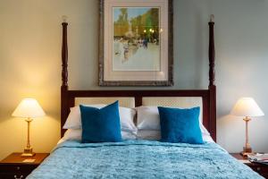 a bedroom with a bed with blue sheets and two lamps at The Bull at Foolow in Hucklow
