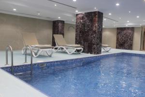 a swimming pool in a hotel room with chairs at فندق اهلا للشقق الفندقية in Al Jubail