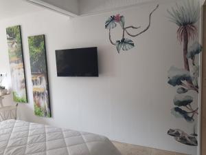 een slaapkamer met een tv aan een witte muur bij Résidence Loanie & Soins in Châlus