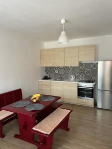a kitchen with two red tables and a refrigerator at Apartman Adriatic BnM in Biograd na Moru