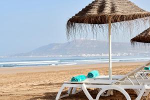 Iberostar Founty Beach All Inclusive في أغادير: كرسي شاطئ ومظلة على الشاطئ