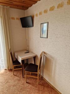 mesa con 2 sillas y TV en la pared en Pension Weghof mit Gasthaus en Böbrach