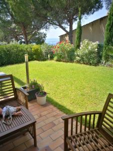 two wooden benches sitting on a patio with a lawn at appartement avec jardin vue sur mer 2 étoiles in Cassis
