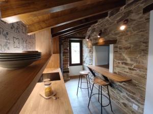 a kitchen with a counter and a stone wall at Casa Fente in Taboada