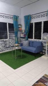 a living room with a blue couch and a table at Ketupat Palas Homestay in Kulim
