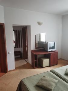 1 dormitorio con TV en un escritorio y 1 cama en Pensiunea Belladonna Baile Olanesti en Băile Olăneşti