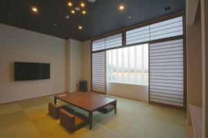 uma sala de estar com uma mesa e uma grande janela em Spa & Hotel Suishun Matsuiyamate em Quioto