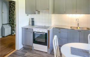La cuisine est équipée de placards gris, d'un évier et d'un four. dans l'établissement 3 Bedroom Awesome Home In Grythyttan, à Grythyttan